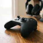 A sleek, modern gaming controller rests on a warm, polished wooden surface